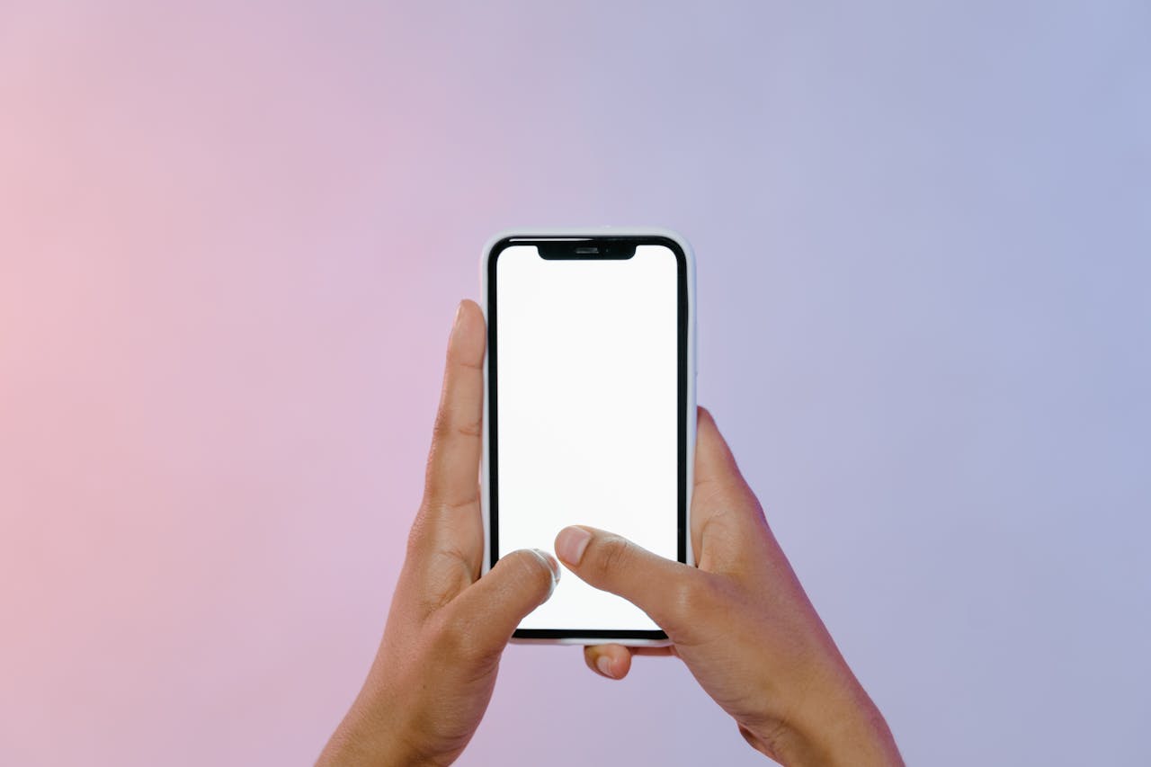 gallery-03 Close-up of hands holding a smartphone with a blank screen, ideal for mockups.